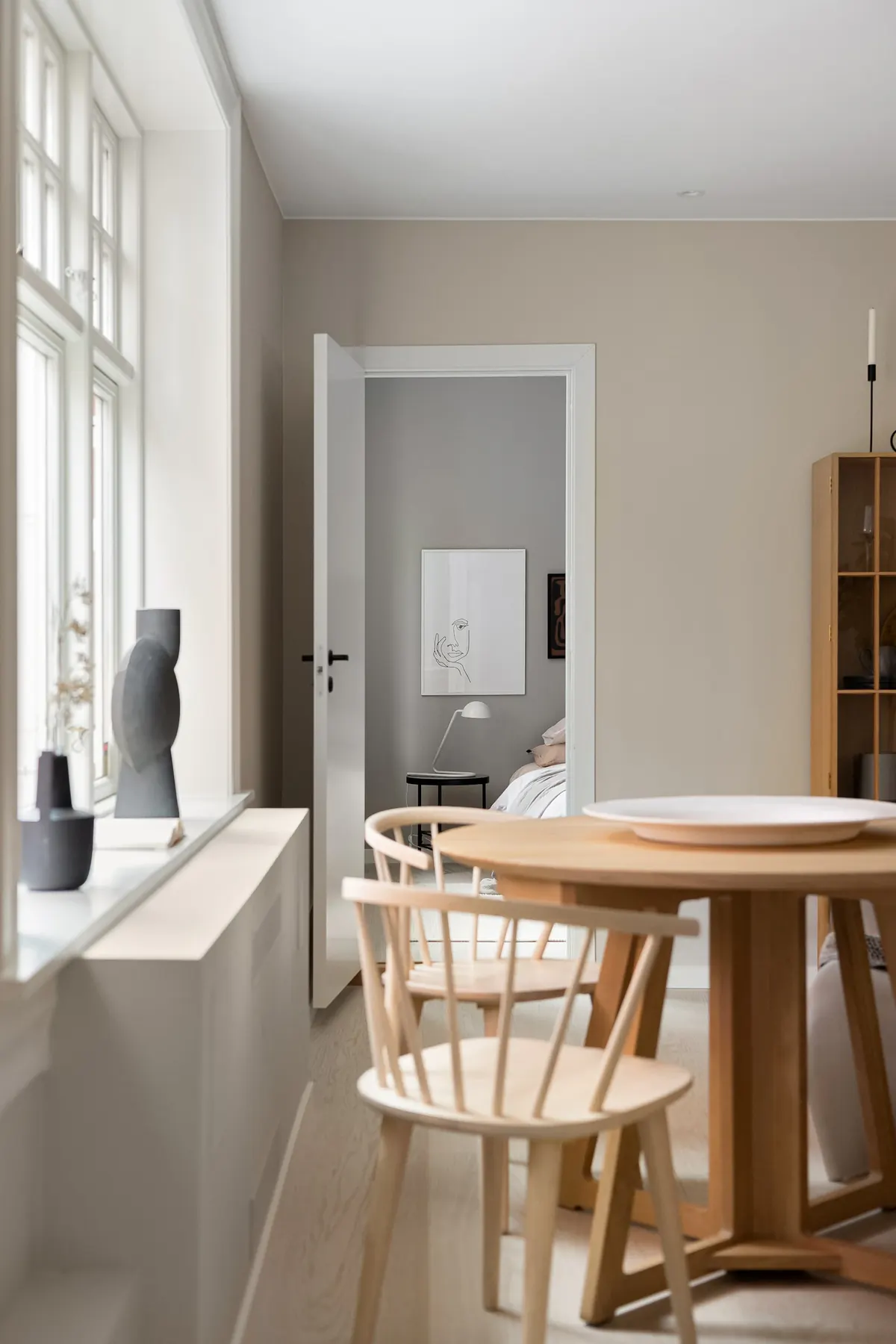 A pale Scandinavian room with a window, light wood table, and two chairs.